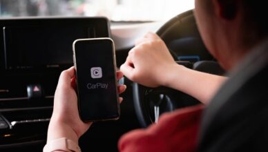 Persoon heeft gsm vast in de auto met daarop Apple CarPlay