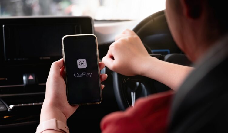 Persoon heeft gsm vast in de auto met daarop Apple CarPlay