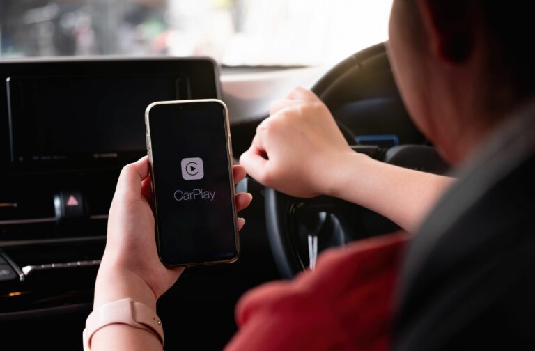 Persoon heeft gsm vast in de auto met daarop Apple CarPlay
