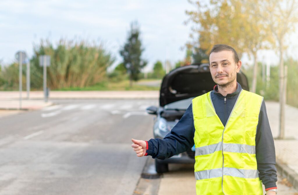 man die zijn duim opsteekt op straat met een fluovestje aan