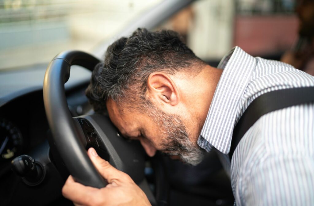 Man die op zijn stuur slaapt in zijn auto