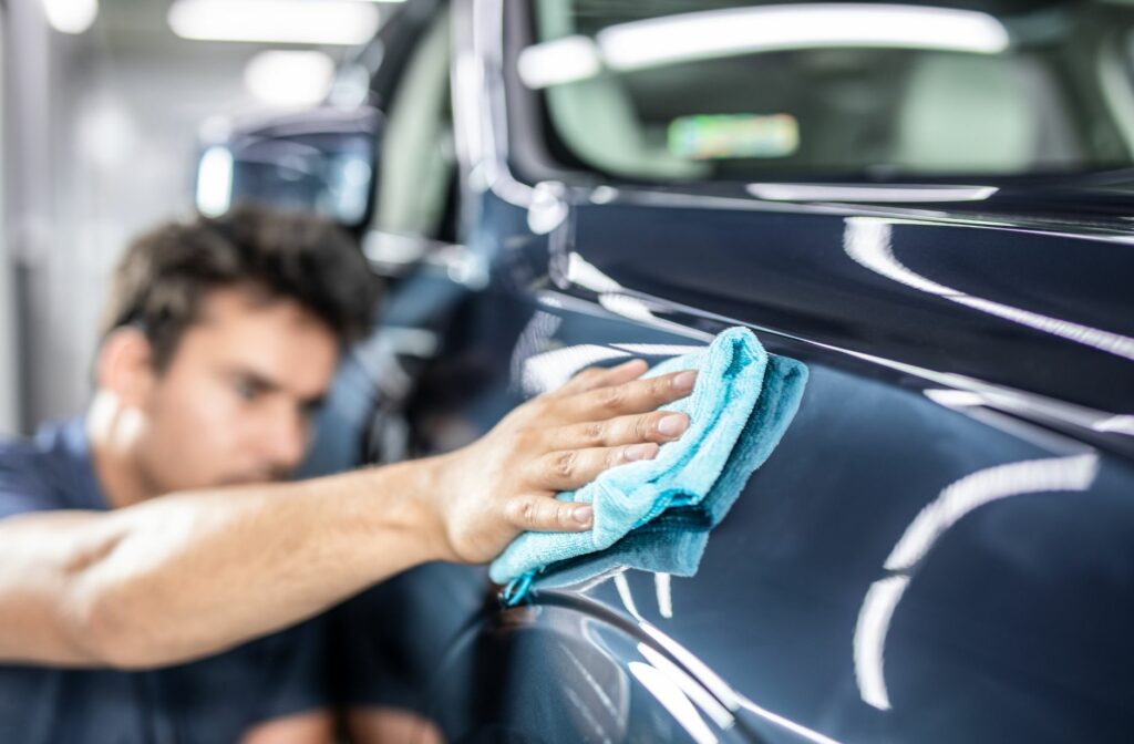 man poetst de buitenkant van een auto