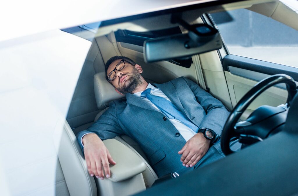 Man in een kostuum die slaapt in een auto