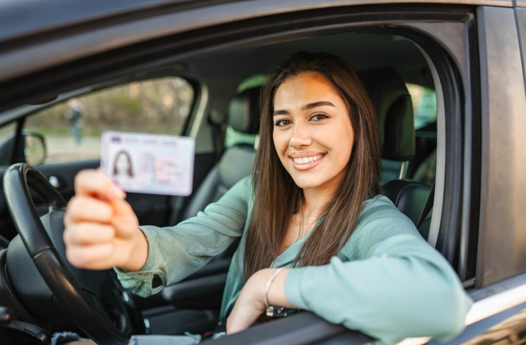 vrouw in een auto die haar rijbewijs laat zien om dat dat verplicht in je auto is