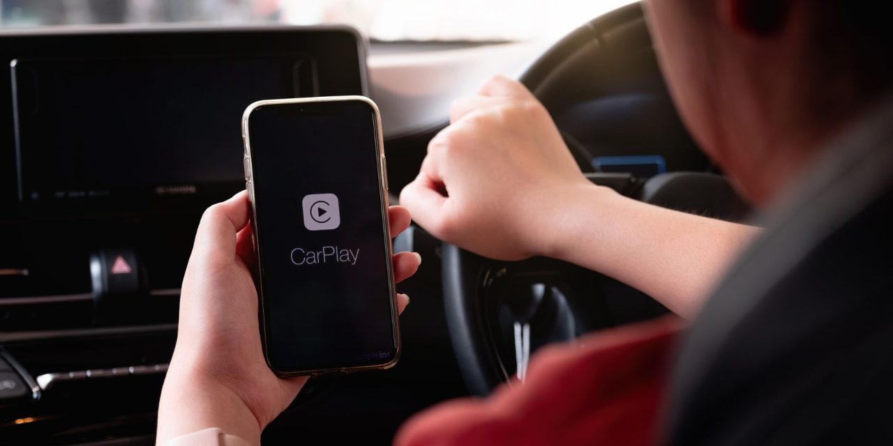 Apple CarPlay Persoon heeft gsm vast in de auto met daarop Apple CarPlay