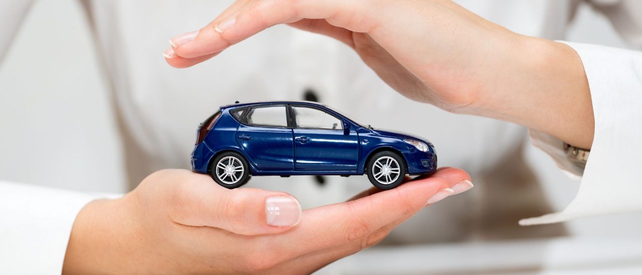 een speelgoedauto wordt tussen 2 handen gehouden om aan te duiden dat het om de verzekeringen voor een bedrijfsauto gaat